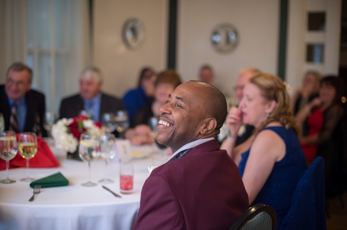 A December Wedding guests smiling as they listen to groom speech